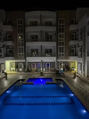 a swimming pool in front of a building at night at Magawish resort in Hurghada