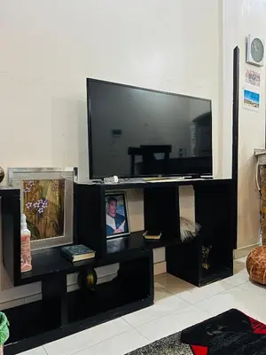 a black entertainment center with a large flat screen tv at Luxor Adventure Guest House in Al Aqālitah