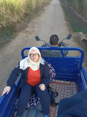 a woman sitting on a blue bench on a road at Luxor Adventure Guest House in Al Aqālitah