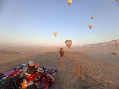 a couple of people flying kites in the desert at Luxor Adventure Guest House in Al Aqālitah