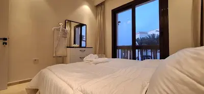 a bedroom with a bed and a large window at El Gouna Luxury 1BR Golf Apartment at Ancient Sands Resort Pool, Beach & Marina Access in Hurghada