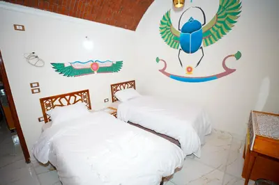 two beds in a room with a painting on the wall at Osman House Luxor in Luxor