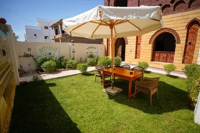 a table and chairs under an umbrella in a yard at Osman House Luxor in Luxor