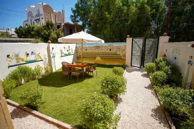 a small garden with a table and an umbrella at Osman House Luxor in Luxor