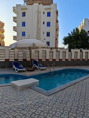 a swimming pool with two chairs and an umbrella at THE BESt in Hurghada