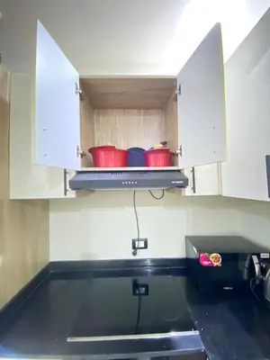 a kitchen with white cabinets and red pots on a stove at alkarma nubia apartment 1521 in Hurghada