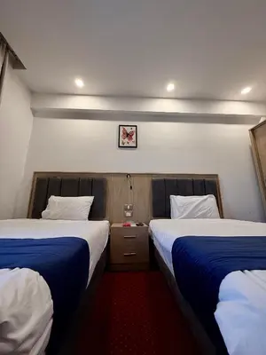 a room with two beds and a picture on the wall at فندق ميريت امون سوهاج in Jazīrat Maḩrūs