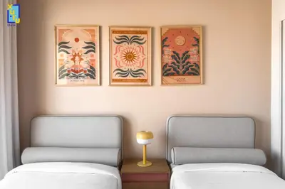 two beds in a room with three pictures on the wall at The 2BDR Blue Horizon Kamaran El Gouna in Hurghada