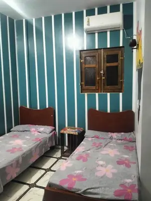 two beds in a room with blue and white stripes at Safy Guest House in Aswan