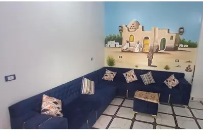 a living room with a blue couch and a mural of a house at Safy Guest House in Aswan