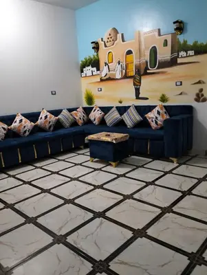 a living room with a blue couch and a painting of a house at Safy Guest House in Aswan