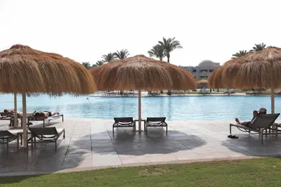 people laying in chairs and umbrellas next to a pool at Xanadu Club Makadi Bay - High Class All Inclusive in Hurghada