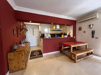 a kitchen with red walls and a table and a counter at Lagoon Charm | 1BR in Steigenberger El Gouna in Hurghada