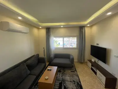 a living room with a couch and a flat screen tv at شاليه بمنتجع ميراج Mirage apartments in Hurghada