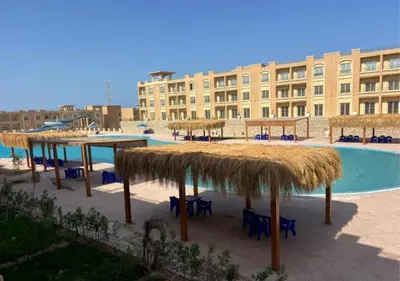 a resort with a pool with tables and straw umbrellas at Bay View Sahl Hasheesh Chalet in Hurghada