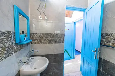 a bathroom with a sink and a blue door at Nubian Spirit in Aswân Reservoir Colony