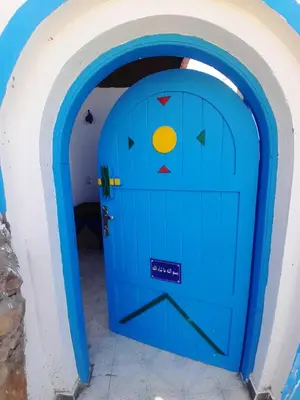 a blue door with a face painted on it at Nubian Spirit in Aswân Reservoir Colony