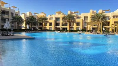a large swimming pool with palm trees and buildings at Mangroovy - 2Br Commodious Pool&Gouna views Condo in Hurghada