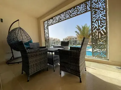 a room with a large window with a table and chairs at Mangroovy - 2Br Commodious Pool&Gouna views Condo in Hurghada