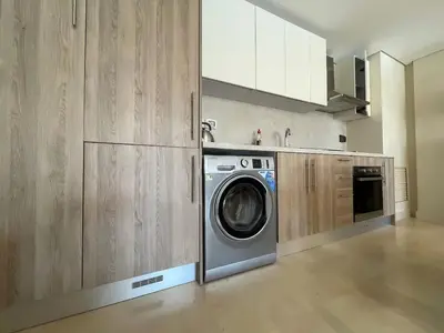 a washing machine in a kitchen with wooden cabinets at Mangroovy - 2Br Commodious Pool&Gouna views Condo in Hurghada
