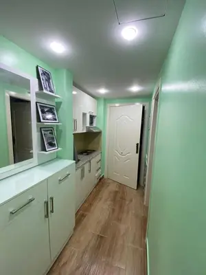 a kitchen with white cabinets and green walls at فلورينزا الخمسين in Hurghada
