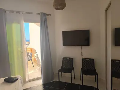 a room with two chairs and a television and a balcony at Royal Beach Resort in Hurghada
