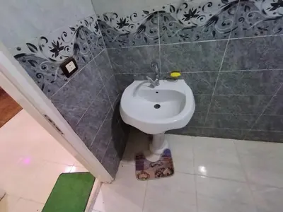 a bathroom with a white sink in a tiled wall at SAMA HOUSE Cozy Mountain Hideaway in Luxor in ‘Ezbet Abu Ḥabashi