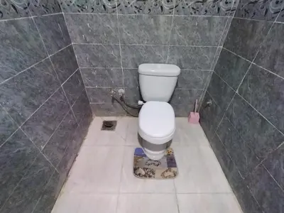 a bathroom with a toilet in a tiled wall at SAMA HOUSE Cozy Mountain Hideaway in Luxor in ‘Ezbet Abu Ḥabashi