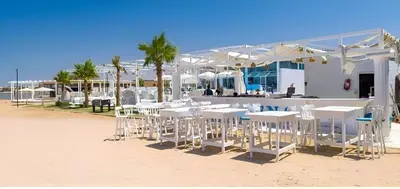 a group of white tables and chairs on the beach at Arena Beach Resort in Hurghada