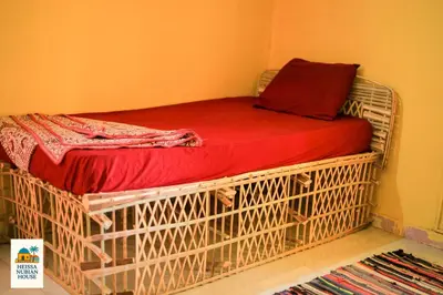 a caged bed with a red blanket on it at Heissa Nubian Hostel in Aswân Reservoir Colony