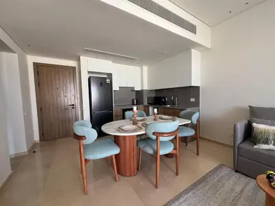 a living room with a table and chairs and a kitchen at Stylish 1BR Retreat – Ancient Sands El Gouna in Hurghada