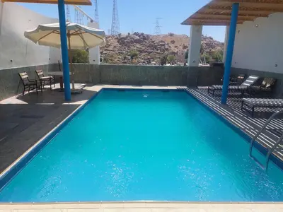 a large blue swimming pool with a table and umbrella at Ashria gest house in Jazīrat Salūjah