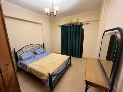 a bedroom with a bed and a green curtain at Cozy Apartment, on Sheraton Road Near Metro Market in Hurghada