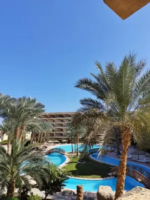 a view of the pool from the balcony of a hotel with palm trees at Relaxing Apartment in Hurghada