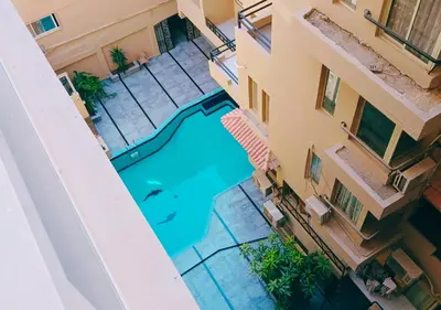 an overhead view of a swimming pool between two buildings at Cozy 1BR Pool View Apartment Steps from the Beach in Hurghada