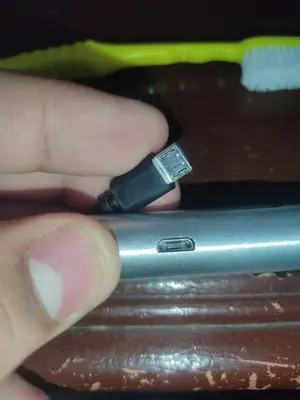 a person is holding a usb cable on a cell phone at الجيار in Qena