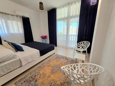 a bedroom with a bed and a chair and windows at The White Lions Villa in Hurghada