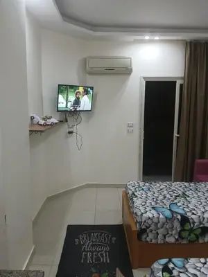 a room with a tv on a wall with a bed at كذا بلانكا بيتش417 in Hurghada