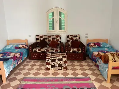 a room with three beds and a couch and a window at ايـو كـاتو in Jazīrat ‘Awwāḑ