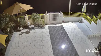 a patio at night with a fence and an umbrella at Esmerada in Aswan