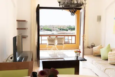 a living room with a view of a balcony at Nayah Stays, Cozy lagoons terrace one ensuite Apt in Hurghada