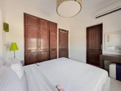 a bedroom with a white bed and wooden cabinets at Nayah Stays, Cozy lagoons terrace one ensuite Apt in Hurghada