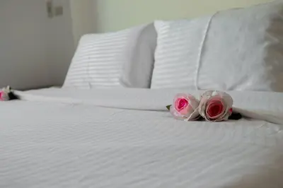 two roses sitting on top of a white bed at Nayah Stays, Cozy lagoons terrace one ensuite Apt in Hurghada