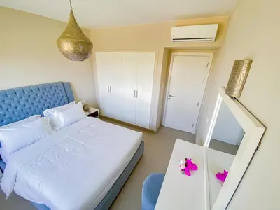 a bedroom with a bed and a table with flowers on it at Nayah Stays, Joubal Lagoons Terrace in Hurghada