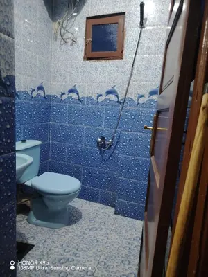 a blue tiled bathroom with a toilet and a window at Venti house in Aswan