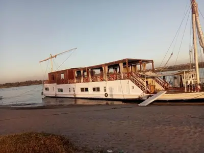 a boat is docked on the shore of the water at Dahabiya Nile Cruise in Luxor