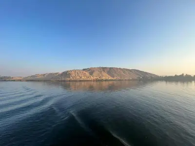 a large body of water with a mountain in the background at Dahabiya Nile Cruise in Luxor