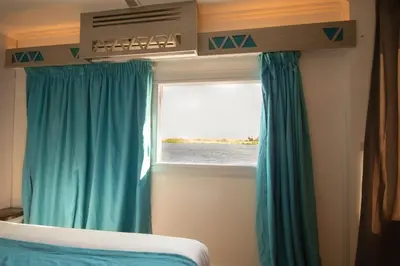 a bedroom with blue curtains and a window at Dahabiya Nile Cruise in Luxor