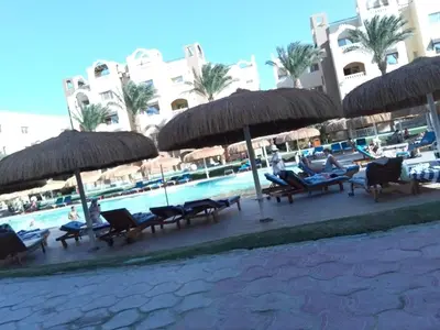 a group of chairs and umbrellas next to a swimming pool at Karma Aqua Beach in Hurghada