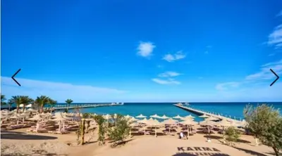 a beach with chairs and umbrellas and the ocean at Karma Aqua Beach in Hurghada